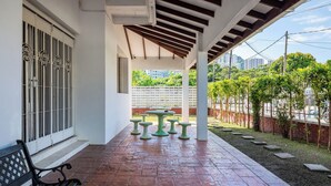 A covered patio area with a table and benches, a bench, and a gated entrance. - GAIA Hotel (George Town)