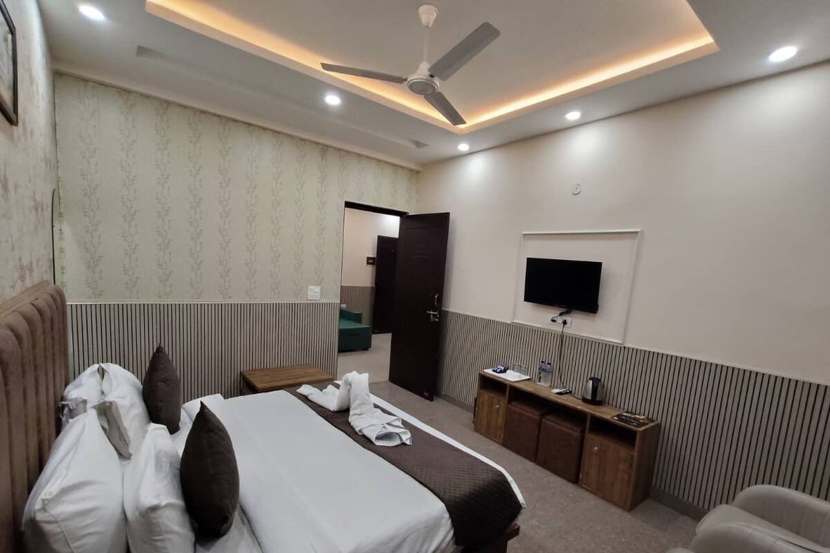Une chambre d’hôtel comprenant un lit, une table de chevet, une télévision et un bureau avec une chaise.