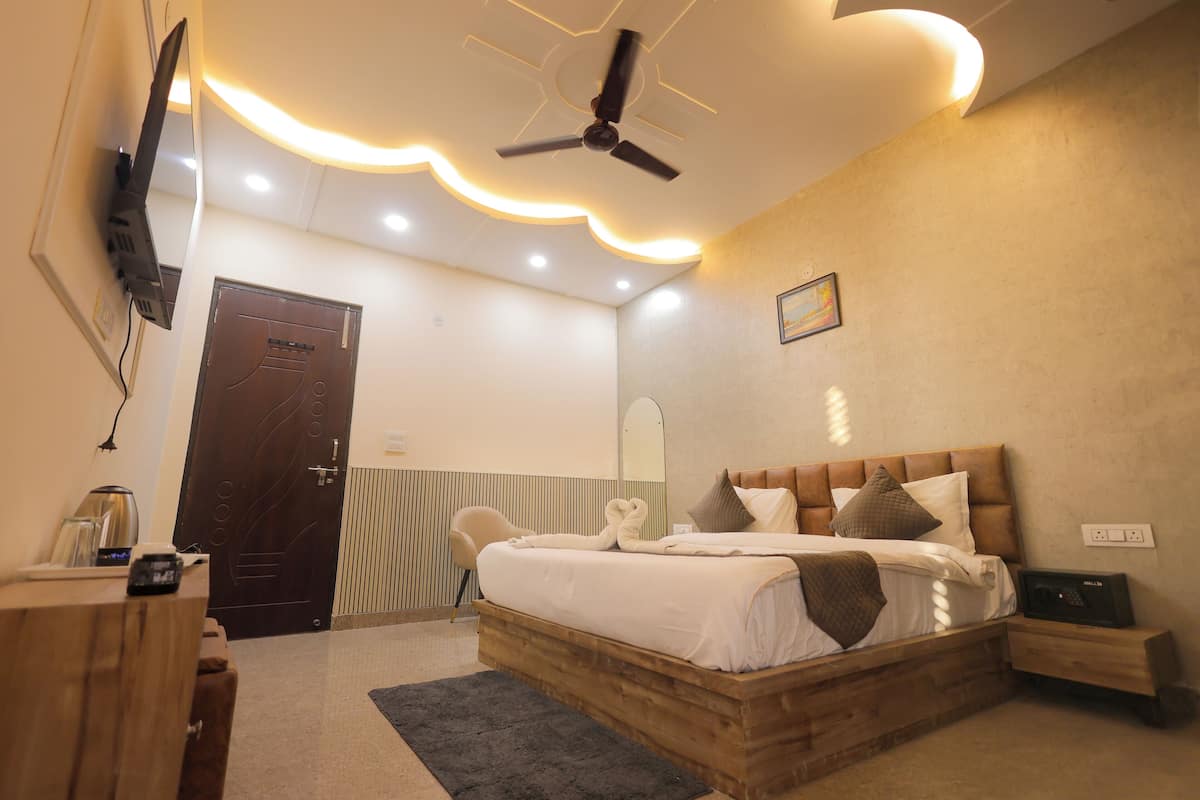 Une chambre à coucher avec un lit en bois, un ventilateur de plafond, un téléviseur fixé au mur et une table de chevet avec une lampe.