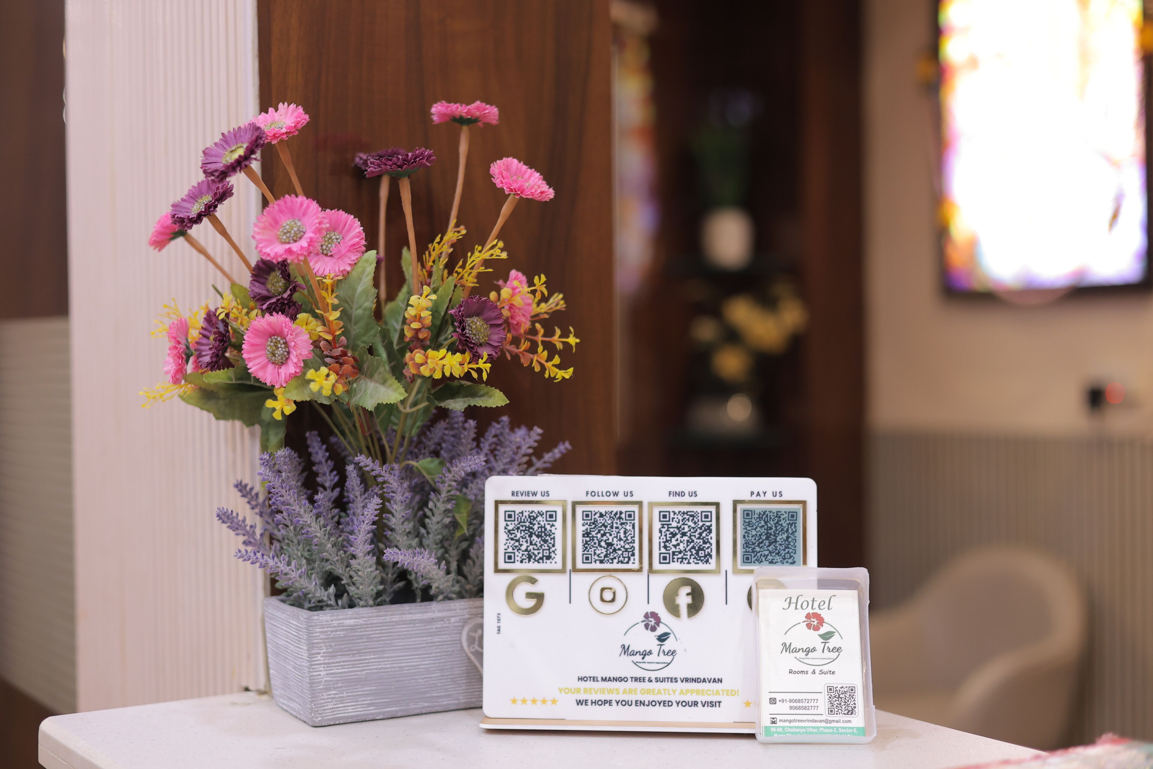 A table with a floral arrangement and a printed card with QR codes and hotel information.