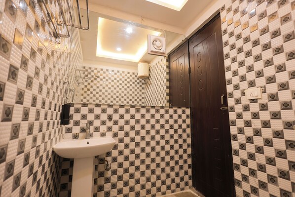 A bathroom with checkered tile walls, a white sink, and a dark wooden door.