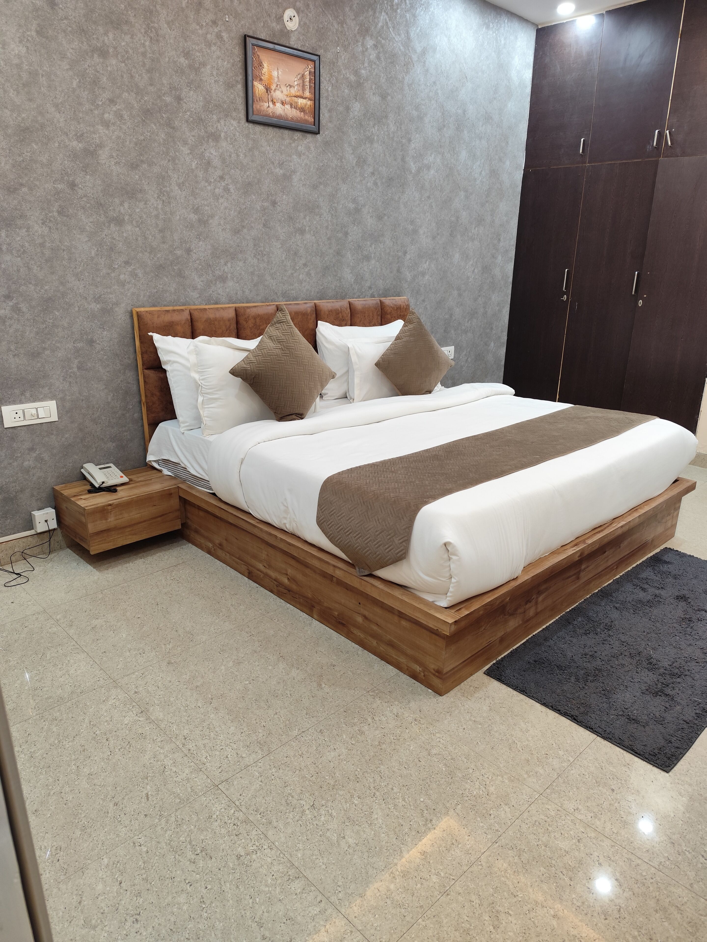 A bedroom with a large bed, wooden headboard, and a dark wardrobe.