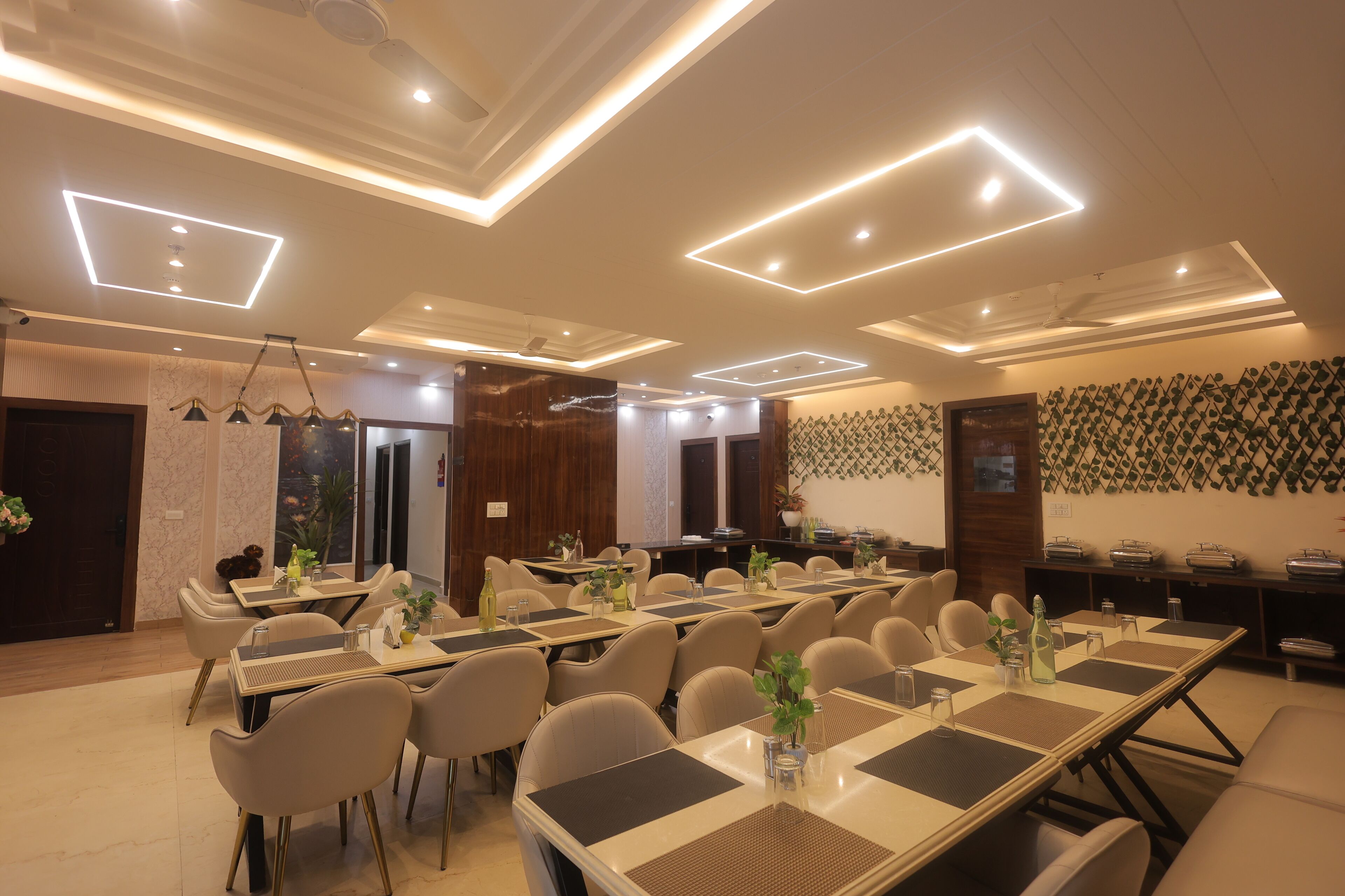 A spacious conference room with multiple tables and chairs, equipped with modern lighting and a decorative wall pattern.