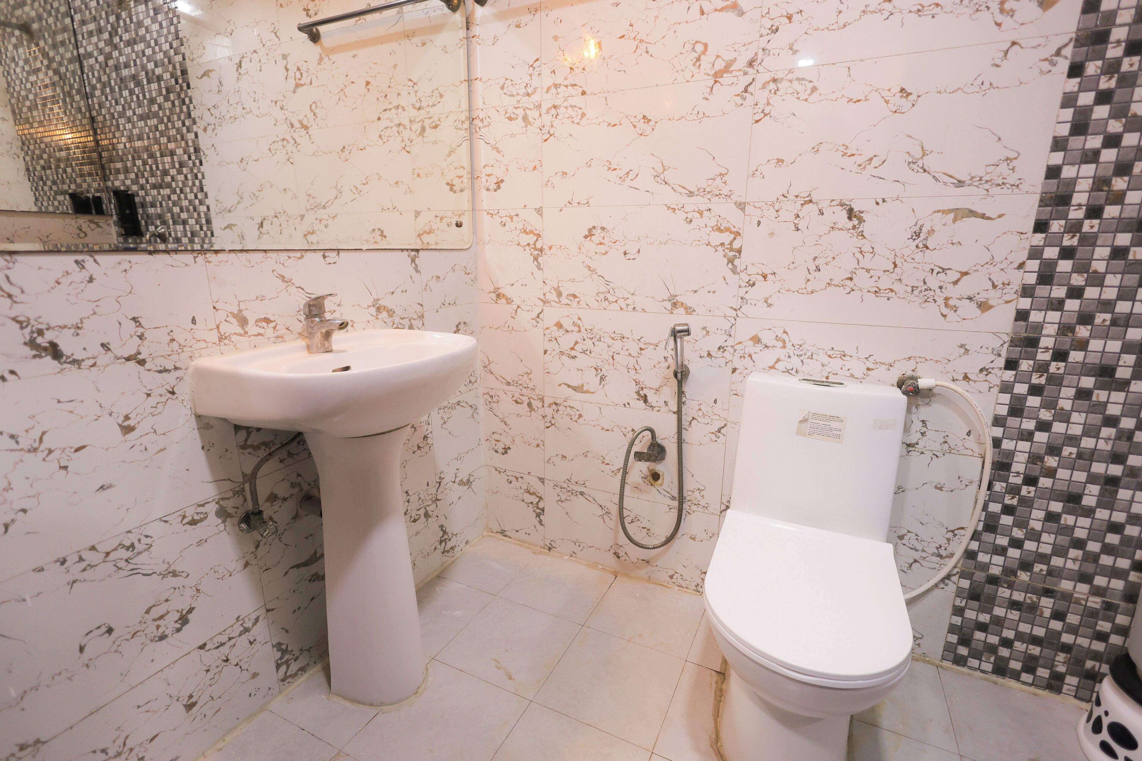 A bathroom with a white pedestal sink, a toilet, and a shower area.