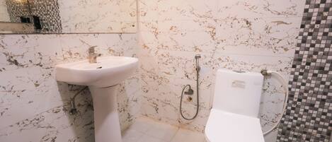 A bathroom with a white pedestal sink, a toilet, and a shower area.