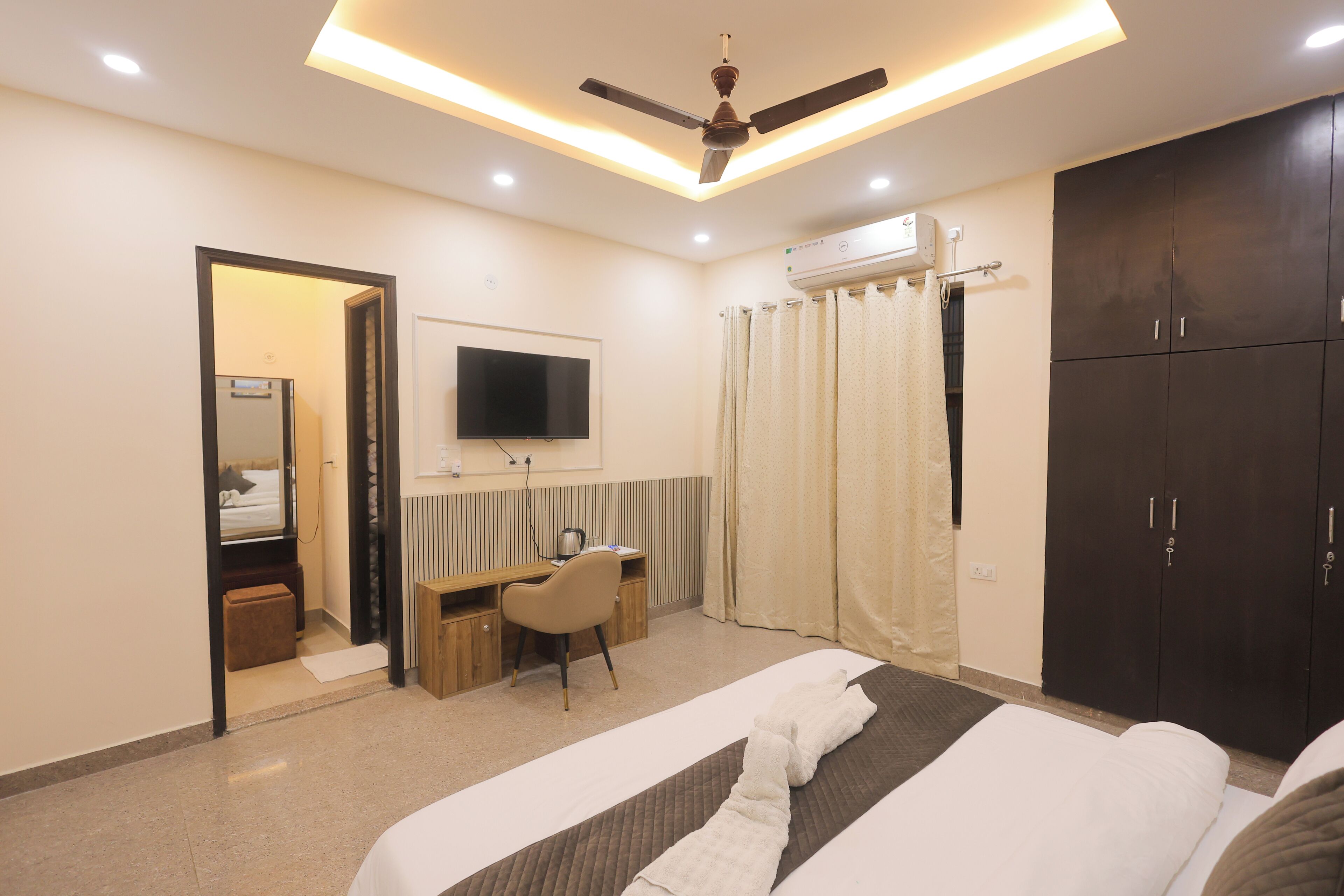 A hotel room with a bed, a desk, a chair, a television, and a wardrobe.