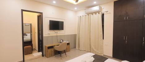 A hotel room with a bed, a desk, a chair, a television, and a wardrobe.
