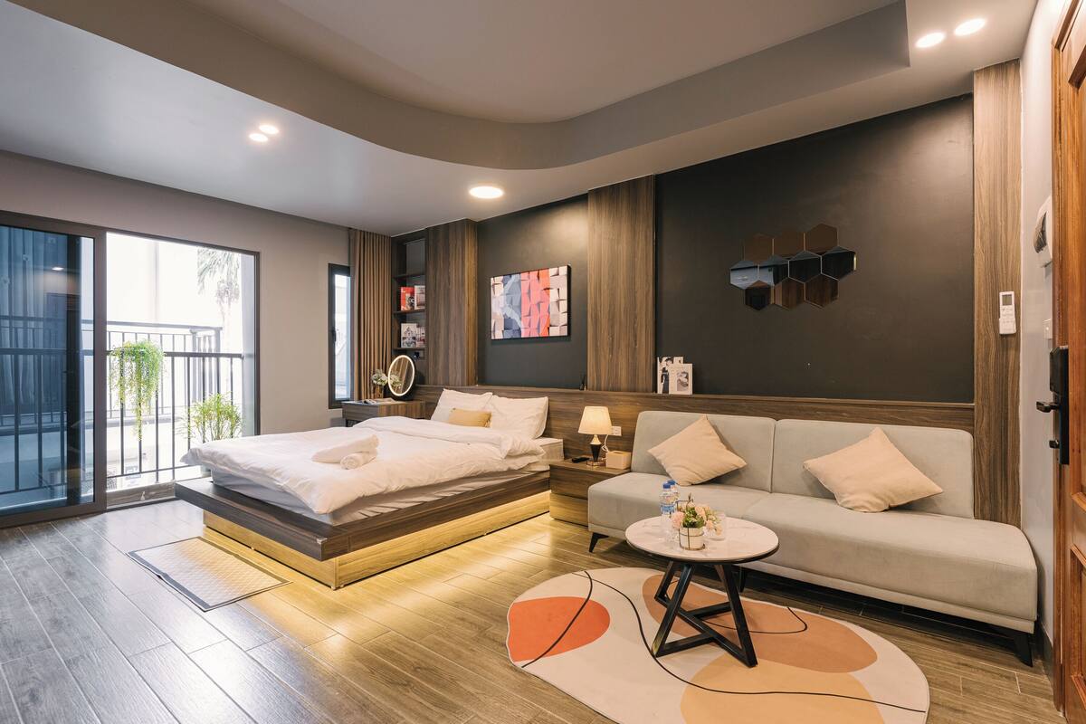 A modern hotel room with a bed, sofa, and a small table.