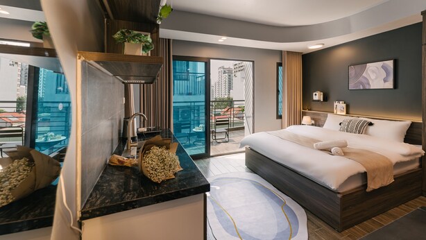 Ein modernes Hotelzimmer mit einem großen Bett, einer Küchenzeile und einem Balkon mit Blick auf die Stadt.