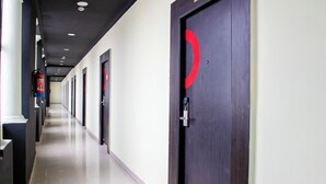 Un pasillo largo y estrecho con puertas a un lado y un extintor en la pared.