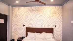 Una habitación de hotel con una cama, un ventilador de techo y una pared estampada.