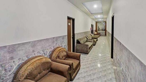 A hotel corridor with rows of brown upholstered chairs and a marble-tiled floor. - Hotel SkyView (New Delhi)