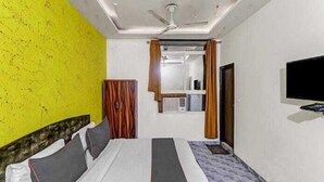A room with a bed, a wardrobe, a television, and a ceiling fan. - Hotel SkyView (New Delhi)