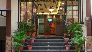 L’entrée d’un hôtel, avec un escalier, des plantes en pot et une enseigne au-dessus de la porte.