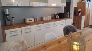Una cocina moderna con armarios blancos, encimera de madera y varios electrodomésticos.
