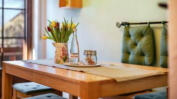 Una mesa de madera con un jarrón de tulipanes, una botella de vidrio y un frasco pequeño.