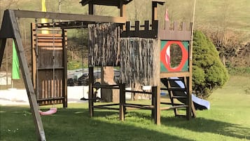 Ein Spielplatz mit Rutsche, Kletterbereich und einer Burgkonstruktion.