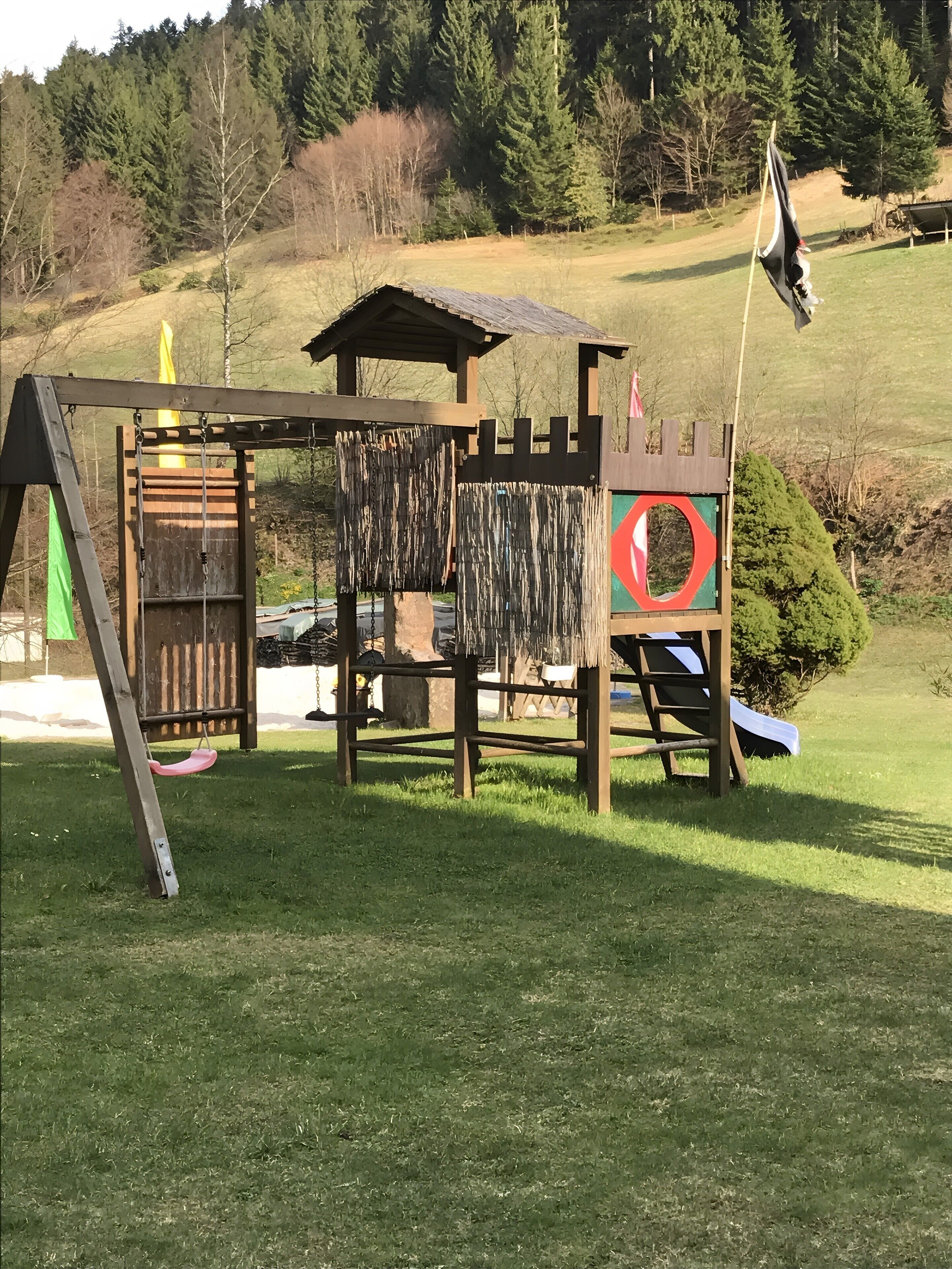 Ein Spielplatz mit Rutsche, Kletterbereich und einer Burgkonstruktion.