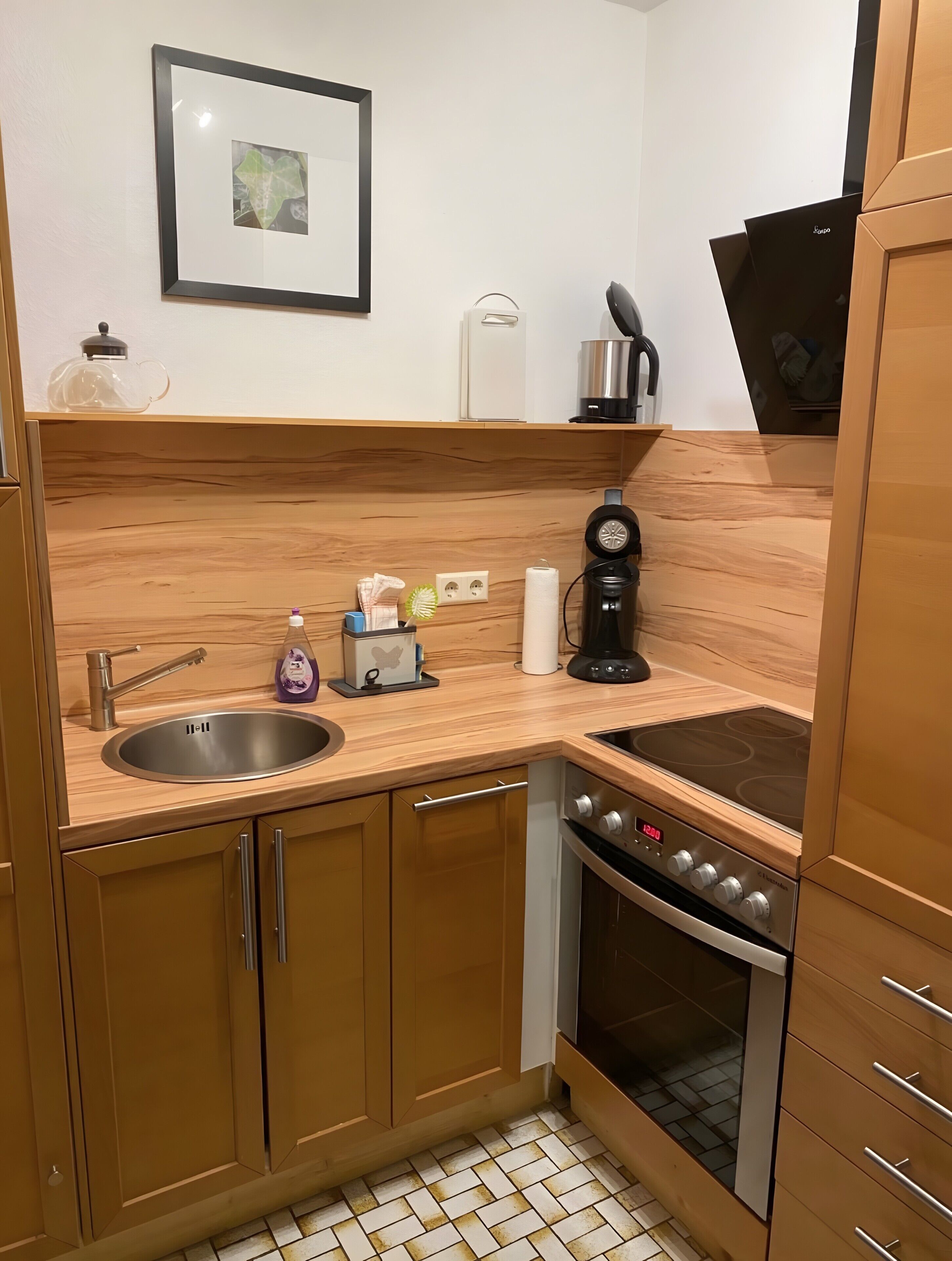 A compact kitchen with a sink, stove, and a coffee maker.