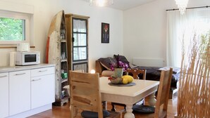 Un coin repas avec une table en bois, des chaises, un vase de fleurs et un four à micro-ondes posé sur le comptoir.