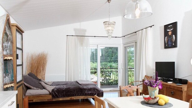 Une chambre avec un lit, une table à manger, un téléviseur et un balcon avec vue.