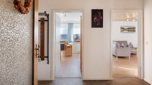 A hallway with a wooden ceiling, a door with a textured glass panel, and a view into a living area with a sofa and a table. - Apartment 'Mit Terasse 110qm' with Mountain View, Private Terrace and Wi-Fi (Schluchsee)
