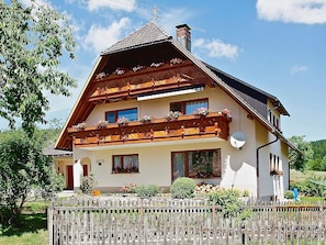 Eine zweistöckige Chalet mit Holzbalkonen, einem geneigten Dach und einer Sat-Anlage.