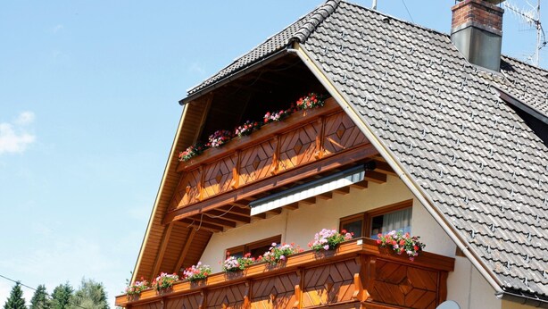 A two-story building with a sloped roof, wooden balconies with flower boxes, and a satellite dish. - Apartment 'Mit Terasse 110qm' with Mountain View, Private Terrace and Wi-Fi (Schluchsee)