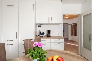 Une cuisine moderne avec des meubles blancs, un plan de travail en bois et un coin repas avec une table mise pour deux personnes.