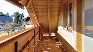 Een houten balkon met uitzicht op de omgeving.