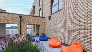 An outdoor seating area with a brick wall, a bench, and two bean bags. - 2 Bedroom Duplex Apartment (Sheffield)