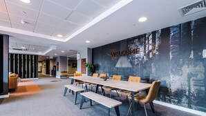A modern conference room with a long table, benches, and comfortable chairs. - 2 Bedroom Duplex Apartment (Sheffield)