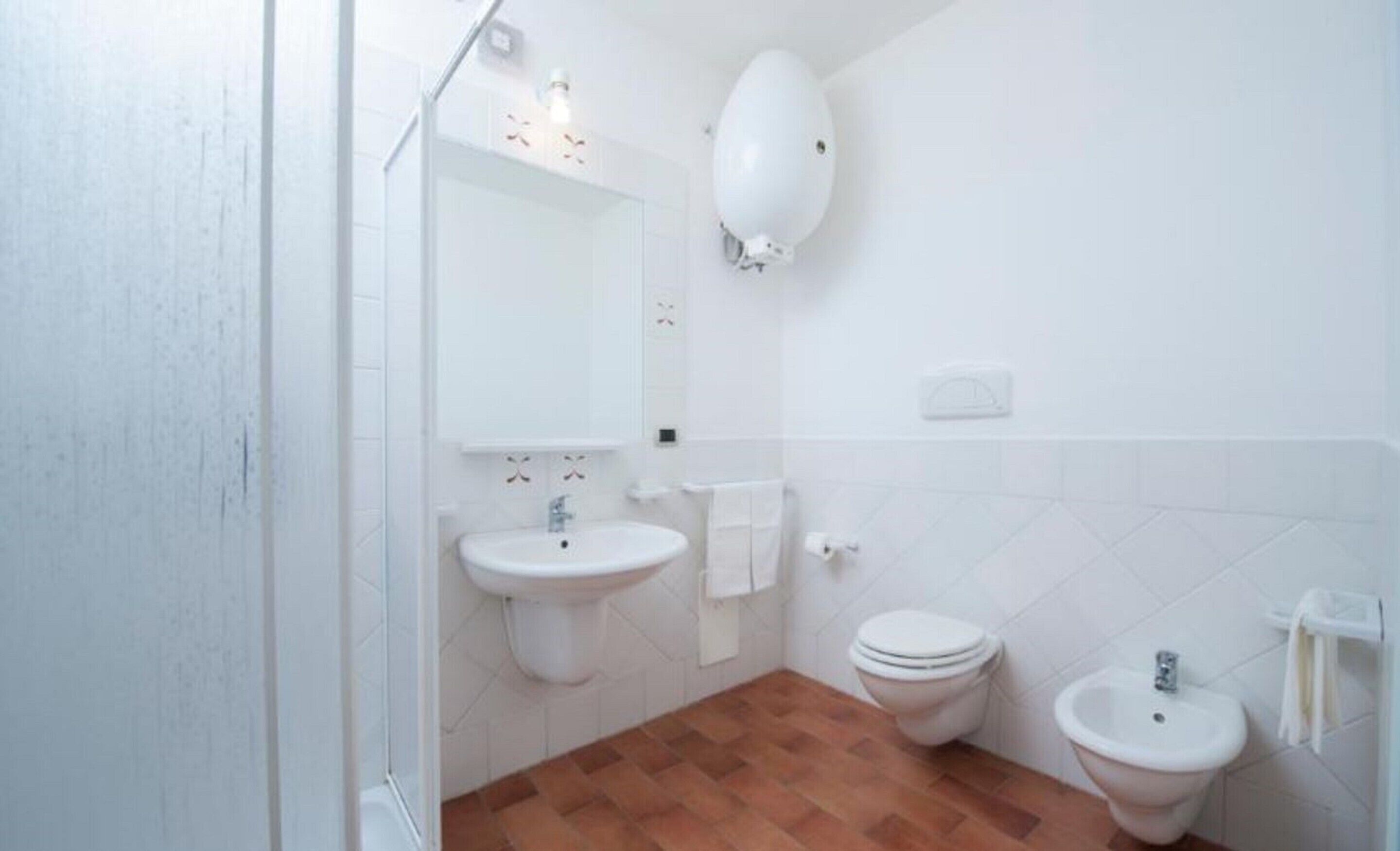 A bathroom with a sink, toilet, and bidet.