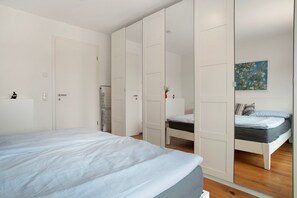 A bedroom with a bed, a wardrobe, and a painting on the wall.