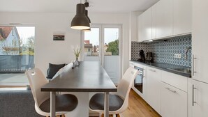 A modern kitchen with white cabinets, a dark countertop, and a dining area with a table and chairs.