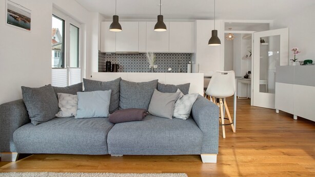 A modern living room with a grey sofa, a wooden coffee table, and pendant lighting.
