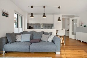 A modern living room with a grey sofa, a wooden coffee table, and pendant lighting. - Holiday Apartment 'Stadt & See' – Arrive, Relax and Enjoy (Lindau)