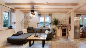 Uma sala de estar acolhedora com sofá, mesa de centro, lareira e cozinha equipada com frigorífico.
