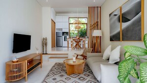 Ein modernes Wohnzimmer mit Flachbildfernseher, Holzkonsole, rundem Couchtisch und einer großen Couch.