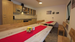 Cucina con mobili in legno, un forno a microonde e un'area pranzo con panche e un tavolo.