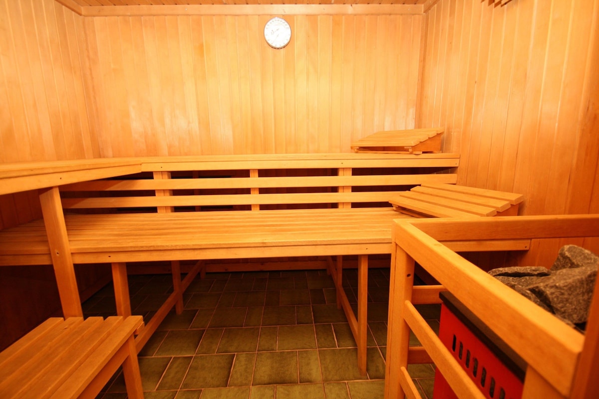 A sauna with wooden benches and a red trash bin.