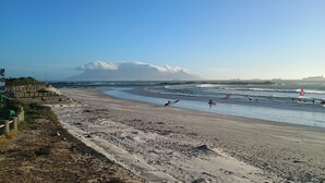 A beach with a clear view of the ocean, a sandy shore, and a distant mountain.