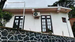Un edificio con fachada blanca, dos ventanas y un equipo de aire acondicionado.