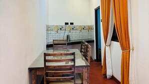 Un comedor con mesa y sillas de madera, un salpicadero de azulejos y cortinas anaranjadas.