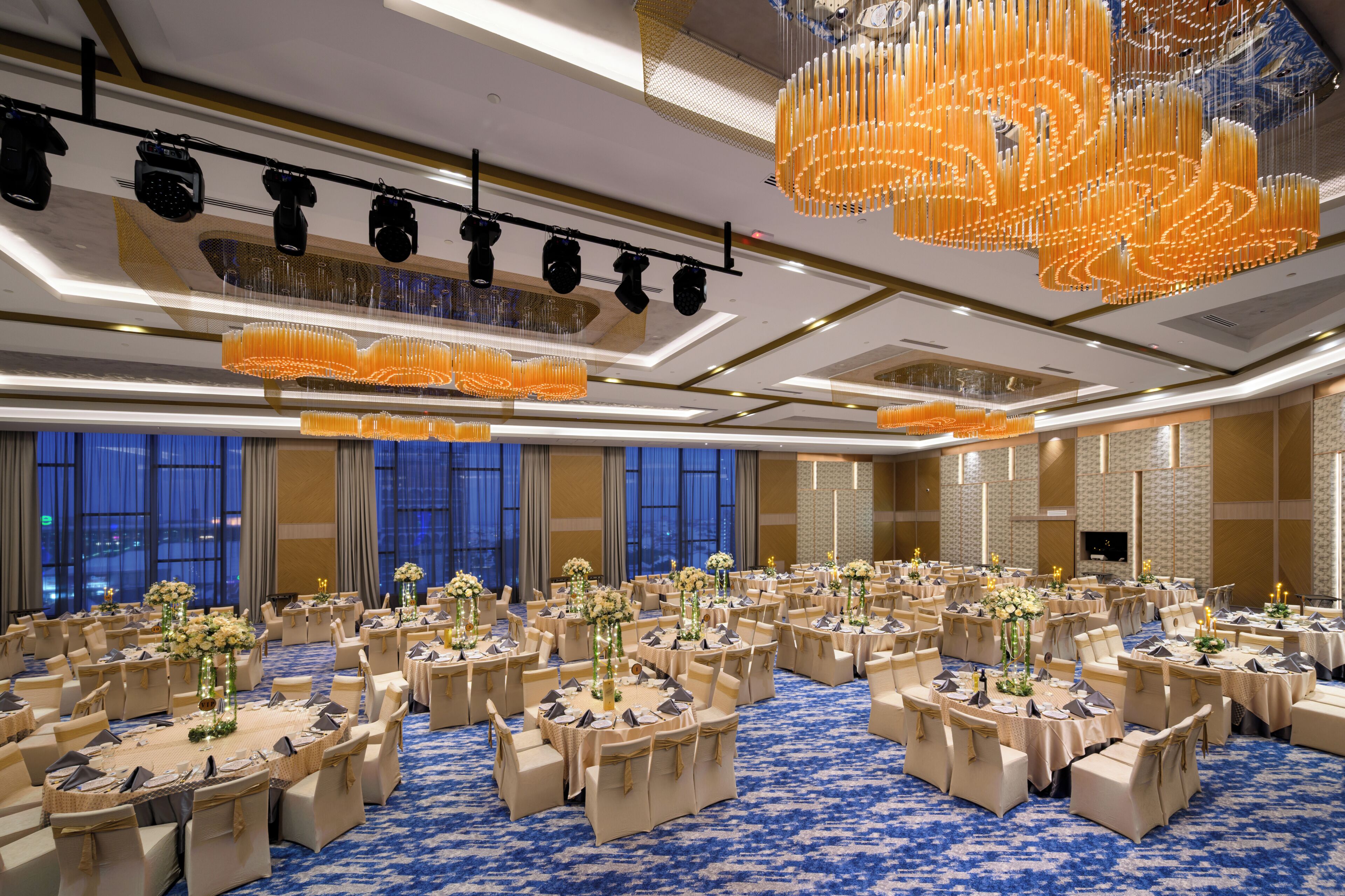 Une salle de banquet avec des tables rondes, des chaises et un tapis bleu.