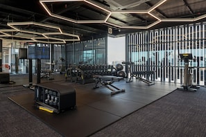 A gym with exercise equipment, a television, and large windows. - Fifth Avenue Hotel (George Town)