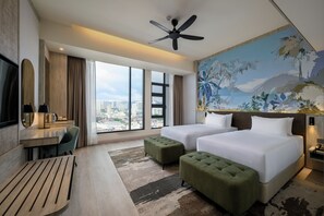 A hotel room with two beds, a desk, a chair, a TV, and a large window with a city view. - Fifth Avenue Hotel (George Town)