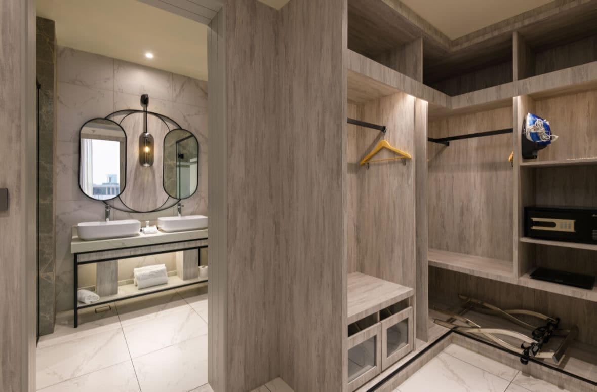 A modern bathroom with dual sinks, a mirror, and built-in shelving.