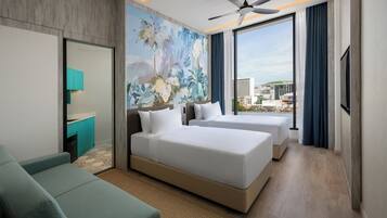 Habitación de hotel con una cama grande, un sofá, un escritorio y vistas de la ciudad.