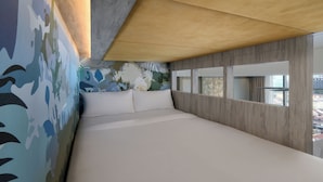 A modern bedroom with a large bed, a wooden ceiling, and a city view through a window. - Fifth Avenue Hotel (George Town)